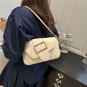 Sac à bandoulière blanc crème rétro avec boucle dorée porté par un mannequin