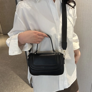 Minimalist black leather saddle handbag with curved decorative stitching and wide strap