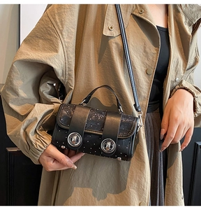 Detailaufnahme einer schwarzen Umhängetasche mit weißen Punkten zum Khaki-Trenchcoat