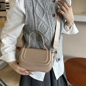 Minimalist beige semi-circle saddle bag with elegant U-shaped stitching and wide strap