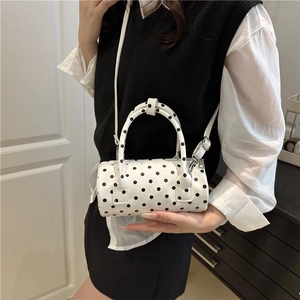 Chic white mini cylinder pillow bag with black polka dots featuring top handles and strap