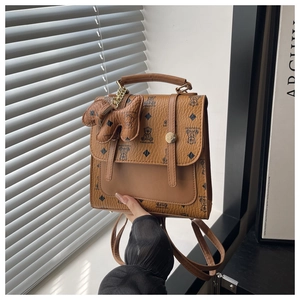 Detail of brown leather backpack featuring bear patterns and a metal twist-lock fastener