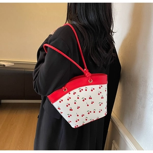 Borsa a secchiello con stampa ciliegia e spalline rosse indossata da una modella in posa