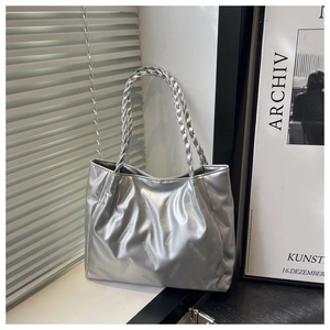 Detail of silver tote bag with embossed metallic texture and braided handle design