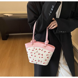 Dettaglio della borsa rosa con stampa ciliegia, manico con nodo e fibbia in metallo
