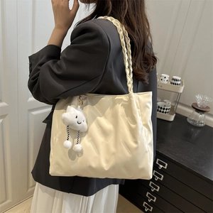 Cream white quilted tote bag with braided handles and a plush cloud charm on model