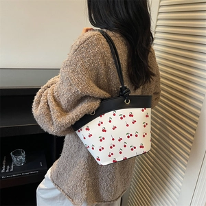 Borsa a secchiello con stampa ciliegia e finiture in pelle nera su modella