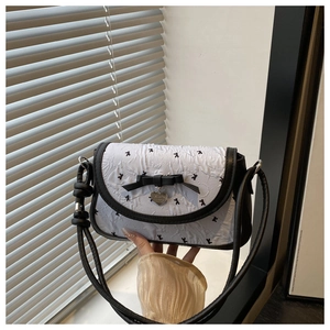Detail of white pleated fabric bag with black bow and silver heart pendant decoration