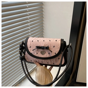 Detail of pink bow handbag with silver heart pendant and black leather trim