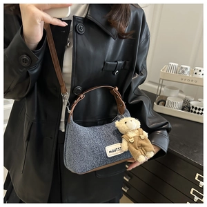 Détail d'un sac demi-lune en jean avec pendentif ours et bandoulière en cuir brun