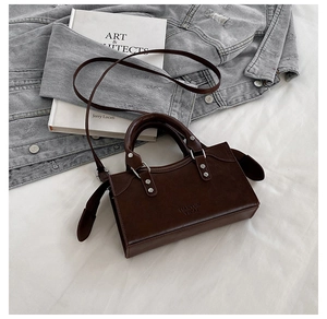 Detail of dark brown glossy leather handbag with embossed logo on a fashion lifestyle setup