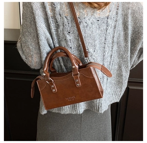 Detail of brown PU leather pillow bag featuring dual handles and embossed logo texture