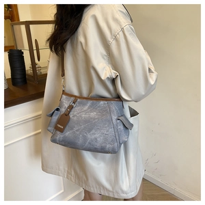 Dettaglio borsa tote in tela grigia con finiture in pelle marrone indossata da modella