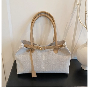 Close-up of large canvas tote bag showing grey fabric texture and leather handle details