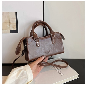 Detail of dark brown leather handbag showing pebble texture and sturdy cylindrical handles