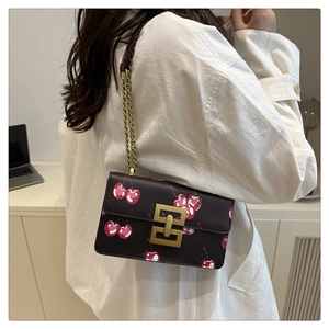 Detail of vintage gold chain strap and metal lock on cherry print crossbody bag