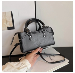 Close-up of black retro textured leather bag with metallic rings and silver rivets detail