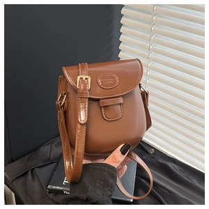 Dettaglio di una borsa a sella vintage in pelle marrone con patta e fibbia in metallo