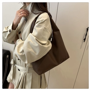 Close-up of deep brown large tote bag with lychee grain texture on a model shoulder