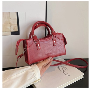 Detail of red square handbag featuring textured PU leather and branded embossed lettering