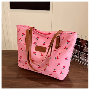 Vue détaillée du sac cabas rose avec imprimé cerise sur une table en bois sombre