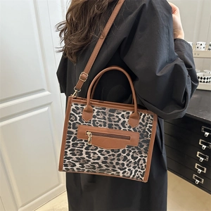 Sac fourre-tout à imprimé léopard avec anses en cuir marron porté par un mannequin