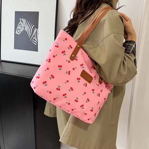 Sac fourre-tout rose à motif cerise avec lanières en cuir porté par un mannequin