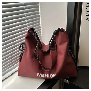 Detail of dark red nylon tote with braided rope handle and FASHION lettering