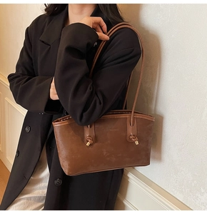 Macro detail of brown matte tote bag with thin leather straps and metal knots