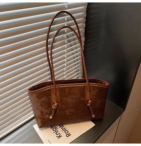 Close-up of brown tote bag showing the distressed texture and elegant knot shoulder straps