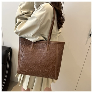 Detail of dark brown tote bag showing woven texture and durable shoulder strap stitching