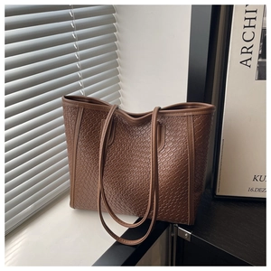Macro detail of brown woven texture on PU leather tote bag with fine stitching