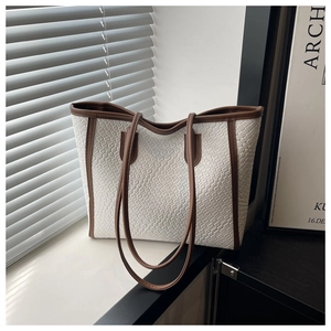 Close-up of white woven checkerboard tote bag with brown leather trim and shoulder straps