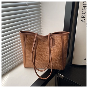 Close-up of caramel woven leather tote bag with elegant diamond texture and thin straps