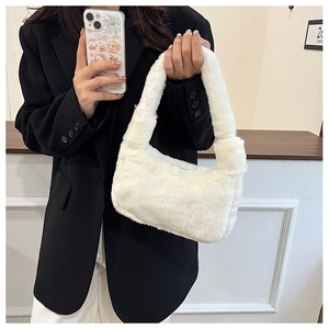 Close-up of fluffy white faux fur shoulder bag worn with a black blazer for winter style