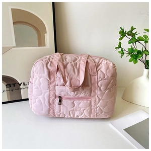 Close-up of pink heart-quilted tote bag with dual handles and front zipper pocket detail