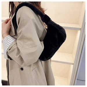 Detailed view of black faux fur underarm bag worn with a stylish autumn beige trench coat