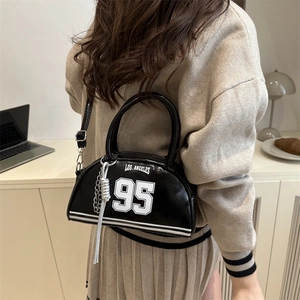 Glossy black croissant bag with Los Angeles print shown on model with shoulder strap