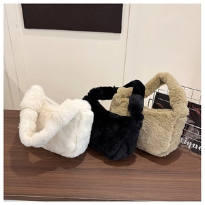 Fluffy plush underarm bags in white, black and khaki displayed on a wood surface