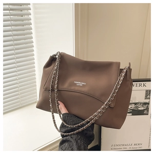 Détail d'un sac bandoulière en cuir mat marron foncé avec chaîne chic et imprimé lettres