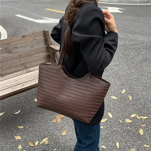Brown woven tote bag with large capacity for women shown in an outdoor autumn setting