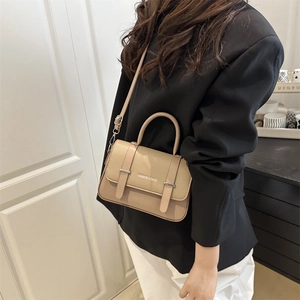 Beige textured leather messenger bag with top handle and fashion brand logo text