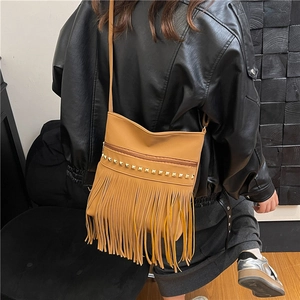 Brown PU leather crossbody bag with golden studs and tassels worn by a model in black jacket