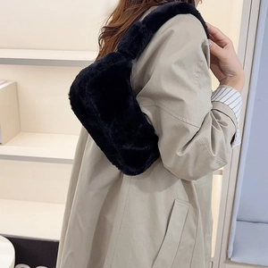 Fluffy black faux fur underarm bag for women shown on shoulder in a stylish autumn setting