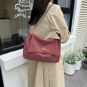 Sac chaîne en cuir rouge foncé minimaliste porté avec un trench beige au style urbain