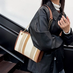Fashion striped tote bag with brown leather trim and metal chain strap on model