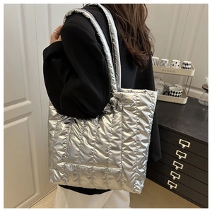 Macro detail of silver quilted tote bag with metallic luster and vertical stitching