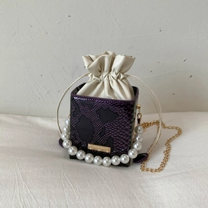 Detail of purple snake-embossed leather bucket bag with white drawstring lining and pearl handle