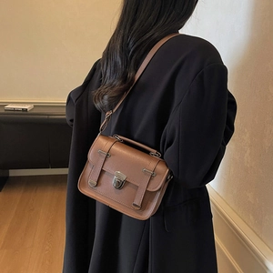 Retro brown leather crossbody handbag with metal buckle and top handle shown on model