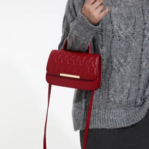 Red PU leather handbag with wavy quilting and gold metal trim on white background